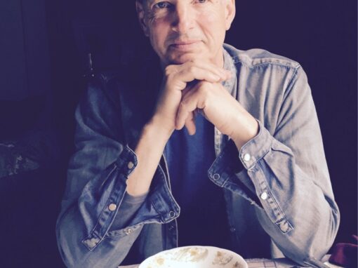 Christopher Marcus, OneSpirit Minister, smiling with a tea cup placed in front of him.