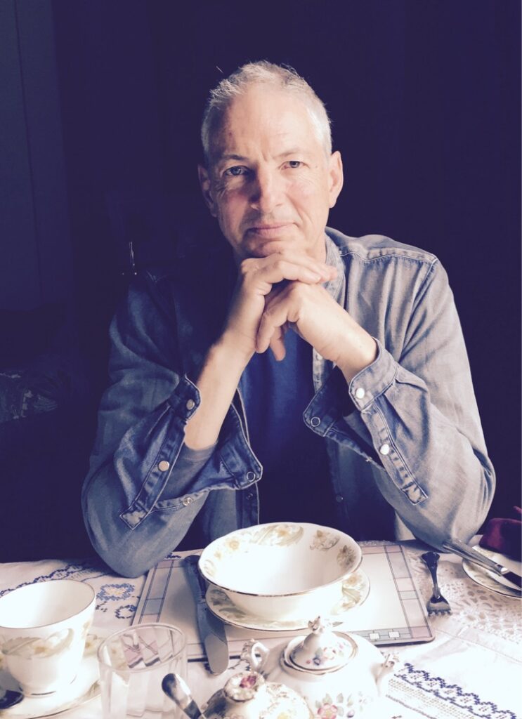 Christopher Marcus, OneSpirit Minister, smiling with a tea cup placed in front of him.