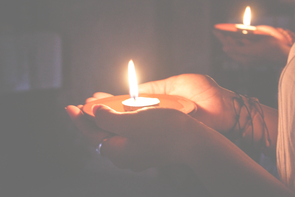 Two people gathered together holding lit candles in their hands.